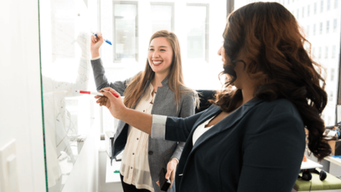 Two coworkers in a meeting discussing the difference between employee engagement and happiness