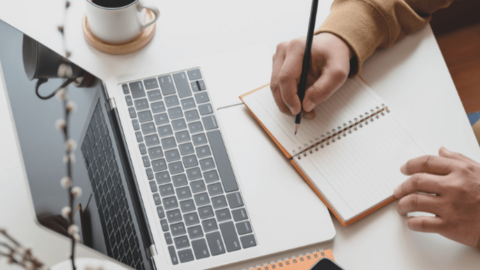 One of the organizers of HeartCount Awards writing in the notebook in front of an open laptop