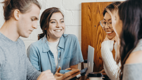 Four colleagues talking and smiling symbolizing happiness at work