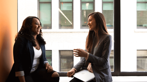 Two happy colleagues chatting about work