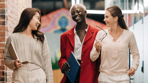 Photo of three women walking and talking about work