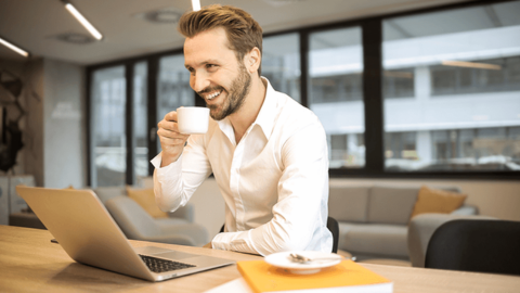 The satisfied business man in a white shirt, with coffee, symbolizes work benefits as one of the factors in how to retain employees.