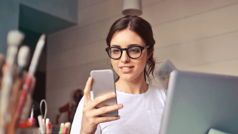 The young woman is looking at her smartphone, potentially searching for ways to reduce employee turnover