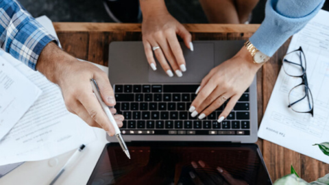 Hands pointing at the laptop screen, choosing the top heart companies by HeartCount, an employee experience app