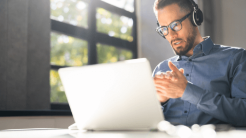 The man is watching his laptop, reading about the webinar 'What Should Your Workplace Learn from COVID-19'