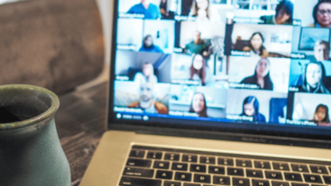 The laptop screen shows a video conference focused on how to keep your organisation happy, with individuals appearing in separate windows