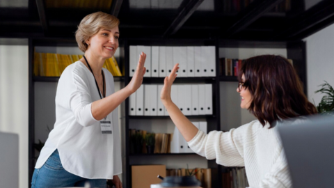 Two employees giving each other a high five symbolizing the importance of recognition in the workplace