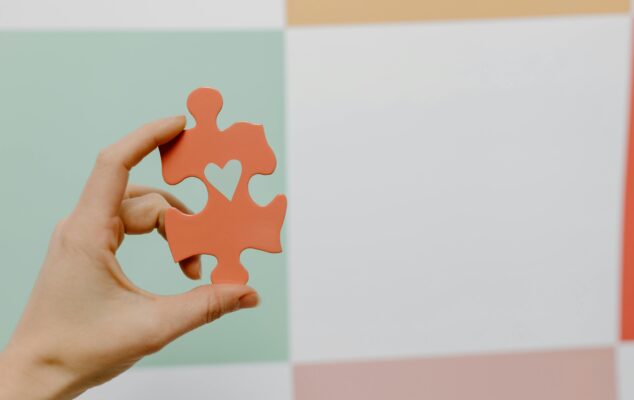 Hand holding a heart-shaped puzzle piece symbolizing employee engagement.